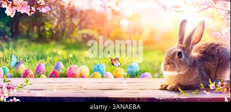 Bunny With Easter Eggs In Spring Meadow Grass - Decorated Eggs In Flowery Field - Abstract Defocused Scene Stock Photo