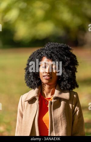 Portrait of a beautiful woman with closed eyes sunbathing on a sunny day of autumn in a public park Stock Photo