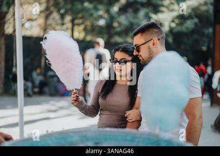 Couple enjoying cotton candy at outdoor fair with sunglasses Stock Photo