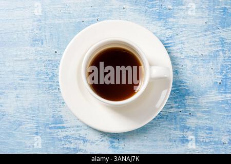 Top view of freshly brewed coffee in white porcelain cup on blue stone table Stock Photo