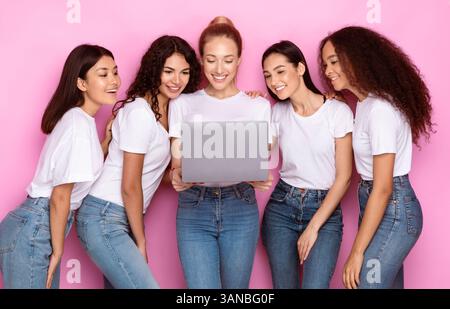 Group Of Multiracial Women Using Laptop Standing Over Pink Background Stock Photo