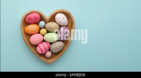 Multicoloured Easter eggs lay in a heart shaped form on a blue background with space for your text, happy Easter. High quality photo Stock Photo