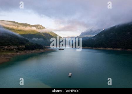 Aerial view of a serene lake with a small island, a fountain, and dense ...