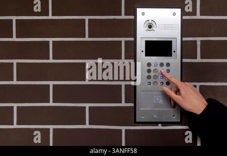 Hand entering code on keypad at building entrance. Space for text. Stock Photo