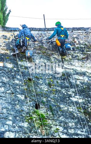 Two building contractors in climbing gear pointing cracks in the stone face of the Chateau in Loches, Indre-et-Loire (37), France. Stock Photo