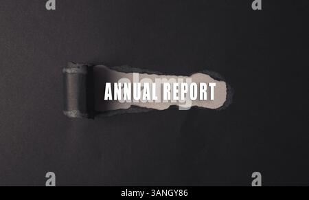 Black and white image of a torn page with the words Annual Report written on it. The image has a mood of destruction and chaos, as if the page has bee Stock Photo