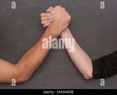 An arm wrestling challenge between a man and a woman. Stock Photo
