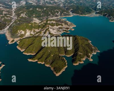 Aerial view of a serene lake surrounded by lush green hills and a ...