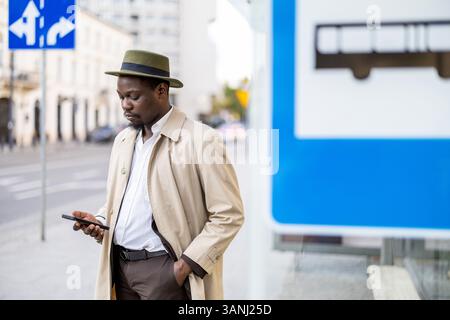 Man using his mobile phone at a bus stop in the city Stock Photo