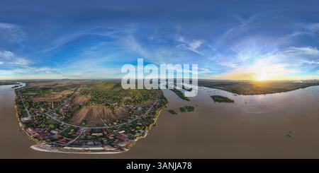 Aerial view of serene sunset over a picturesque river and rural village surrounded by expansive fields and trees, Khong District, Laos. Stock Photo
