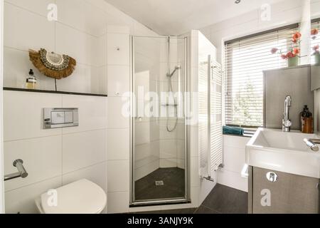 A sleek and contemporary bathroom featuring a walk-in shower, stylish fixtures, and elegant storage solutions, all designed for convenience and aesthetics. Stock Photo