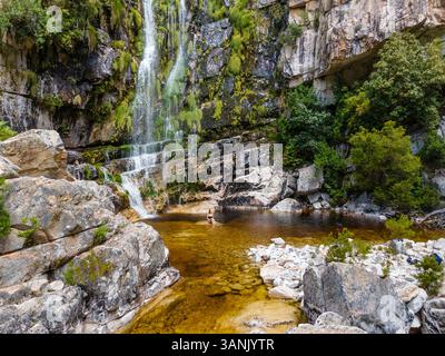 Aerial view of a woman standing in front of a waterfall in black swimsuit, Rawsonville, Western Cape, South Africa. Stock Photo