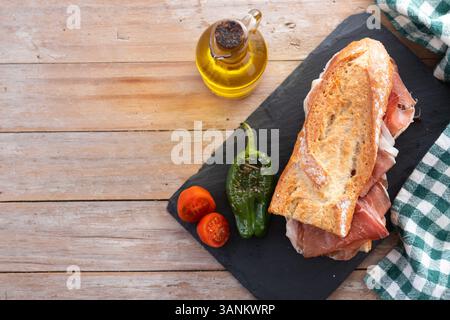 Spanish serrano ham sandwich on wooden table. Spanish bocadillo de jamon serrano. Stock Photo