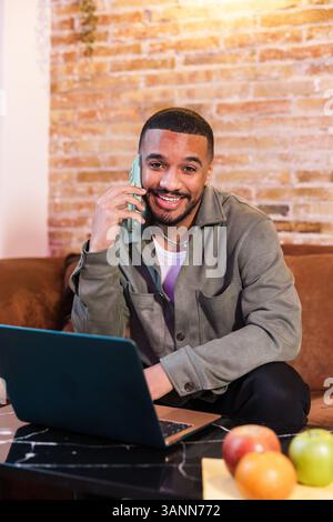 Smiling freelancer working from home and talking on phone Stock Photo