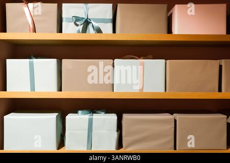 The image features beautifully wrapped gift boxes in pastel colors, neatly arranged on wooden shelves. Stock Photo