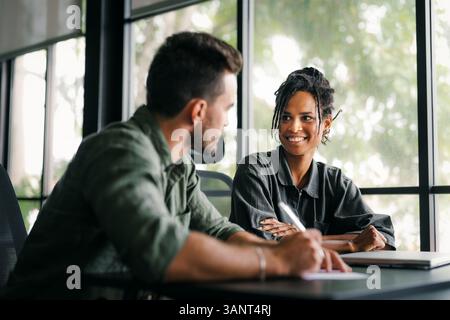 A diverse, talented team collaborates effectively in a bright office space during a business meeting Stock Photo
