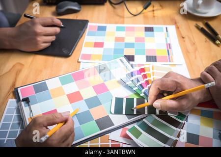 Interior designer chooses a color chart for home design. Graphic designers working on color chart at modern office. Stock Photo