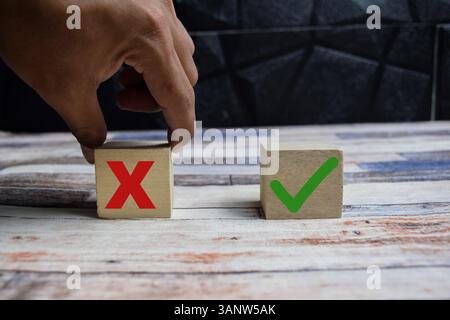 Concept word Yes or No choice symbol. hand making between two cubes with yes and no icon on wooden blocks on a wooden table Stock Photo