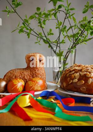 Easter still life containing a small lamb cake, painted eggs, traditional Czech Easter sweet cake called "mazanec", an Easter whip and green twigs Stock Photo