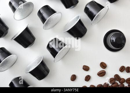 Espresso coffee capsules in rows and coffee beans on a white table. Top view. Stock Photo