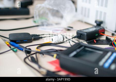 A tangled bunch of wires is currently laying messily on a table, possibly related to electronic devices or gadgets nearby Stock Photo