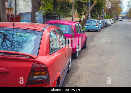 Row of cars parked on roadside. Colorful parked cars lined along urban street in day. Parked cars symbolize daily routine, urban lifestyle, city Stock Photo