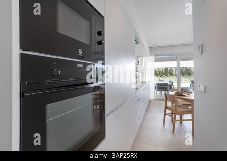 Close-up view of sleek built-in oven and microwave unit in a modern, streamlined kitchen space. Stock Photo