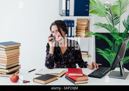 Woman in business suit talking on phone at desk in office training Stock Photo