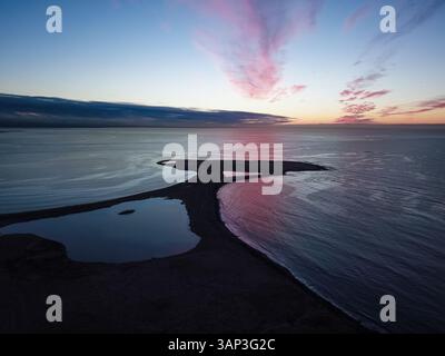 Aerial view of the sunset reflecting off the water over the golf course of Golfklúbbur - Seltjarnarnes, Reykjavik, Iceland. Stock Photo
