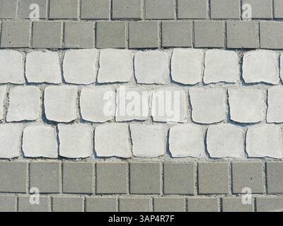 paved surface with white stones hinting at a zebra crossing. Structure and marking provide orientation in the sidewalk area. Stock Photo