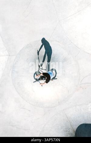 Aerial view of BMX bike rider silhouette shadow in concrete skate pool ...