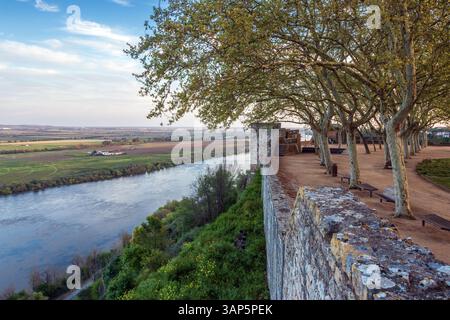 View along the castle wall surrounding the Portas do Sol garden in Santarém, Portugal, with the Tagus River in the background at sunset. Stock Photo