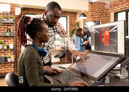 Creative team of black man and woman brainstorming together in modern workspace, collaborating on graphic design projects. African american coworkers utilizing modern technology for multimedia work. Stock Photo