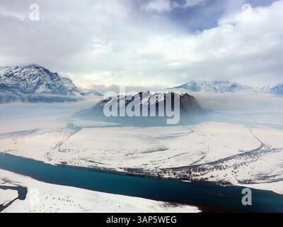 Aerial view of snow-covered mountain, river, and valley under cloudy sky, Skardu, Punjab, Pakistan. Stock Photo