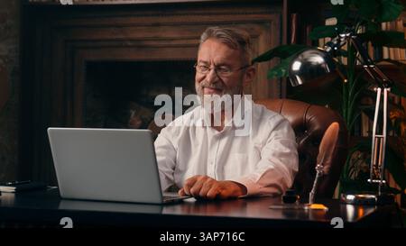 Elderly Caucasian man businessman waving hand greeting online business meeting video conference laptop computer partner call finance internet manager Stock Photo