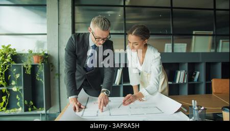 Architects reviewing blueprint in modern office space Stock Photo