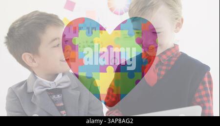 Image of autism awareness month colourful puzzle pieces forming heart over schoolboys Stock Photo
