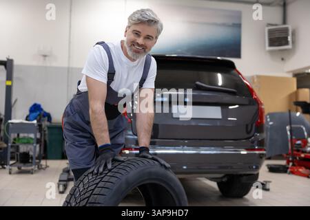 Automotive technician in garage checking wheel and fixing tire ensuring vehicle safety Stock Photo