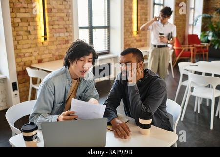 Two professionals engage in a collaborative effort while examining documents together. Stock Photo