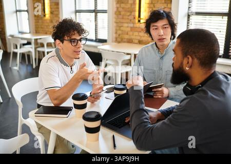 Three professionals exchange ideas in a bright workspace, focusing on teamwork and collaboration. Stock Photo