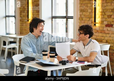 Two people share laughs and ideas at a table in a lively atmosphere. Stock Photo