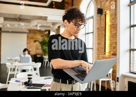 Bright office features a focused individual on a laptop, surrounded by modern decor. Stock Photo