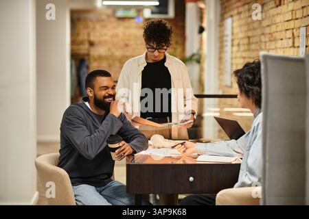 Team members brainstorm over coffee in a bright, modern workspace with natural light. Stock Photo