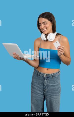 Happy young woman making online purchases using her laptop and credit card, enjoying the convenience of e-commerce Stock Photo