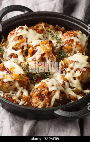 French onion meatballs smothered in rich caramelized onion gravy and topped with melty Gruyere cheese closeup on the pan on the table. Vertical Stock Photo