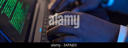Website header shot of hands typing on a laptop keyboard with green code displayed on screen, emphasizing technology and coding process Stock Photo