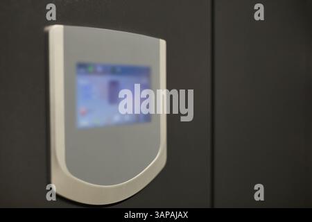 Close-up view of a contemporary device with a digital display screen showing data in a blurred background, featuring sleek design and modern technology Stock Photo