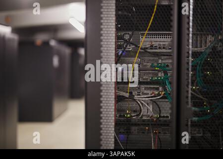 Displaying intricate wiring of server rack inside modern data center. Visible details include network cables and active hardware components in a controlled environment Stock Photo