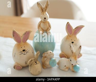 Ceramic figurines of playful bunnies gathered on a table, depicting various adorable poses. The arrangement showcases different sizes and expressions Stock Photo