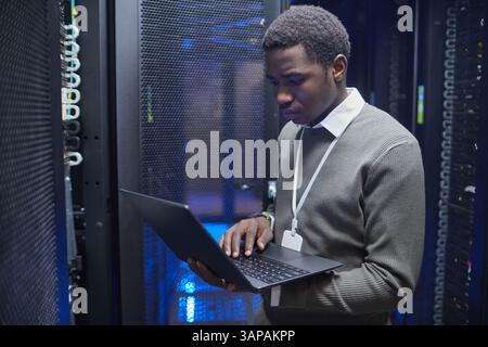 Technician working on configuring server racks inside modern data center, ensuring system functionality and network connectivity Stock Photo